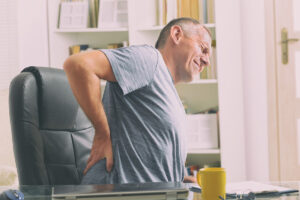 Man in home office suffering from low back pain.