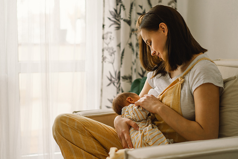 Newborn baby boy sucking milk from mothers breast.